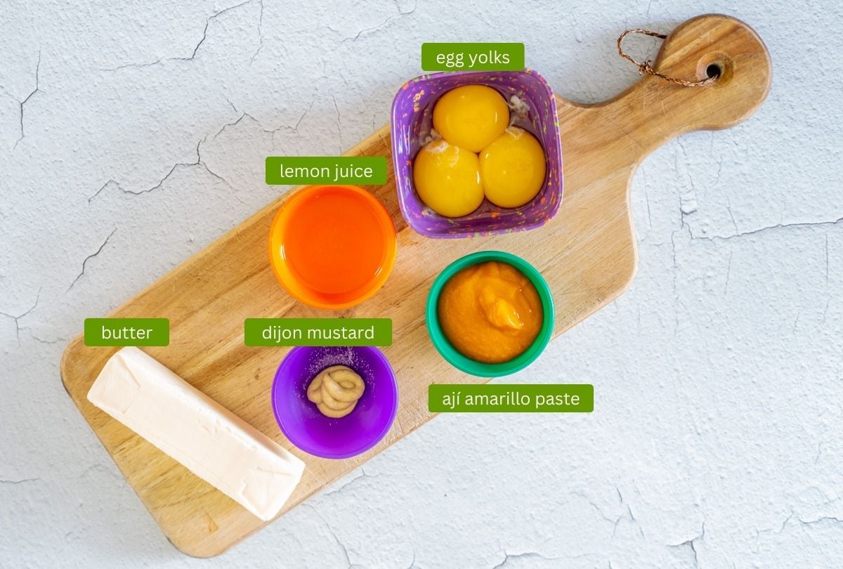 Ingredients for Peruvian blender hollandaise including egg yolks, lemon juice, aj&iacute; amarillo paste, dijon mustard, and butter.