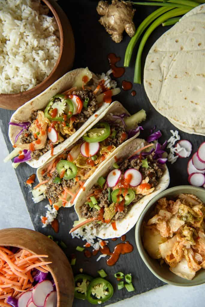 Korean ground beef bulgogi tacos with toppings on a tray.