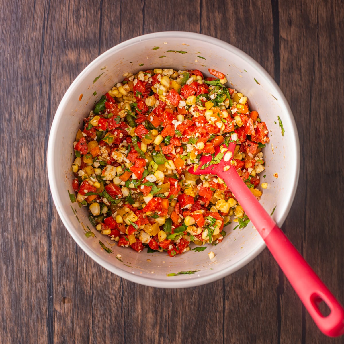 All ingredients are mixed together in a white bowl with red spatula.