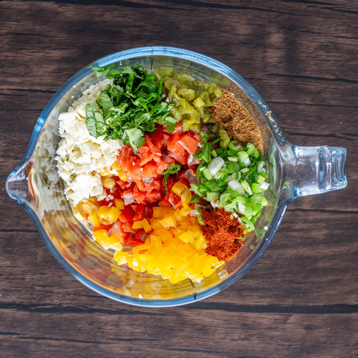 A glass bowl with ingredients for the spicy salmon patties - salmon, scallion, jalape&ntilde;o, cotija, etc.