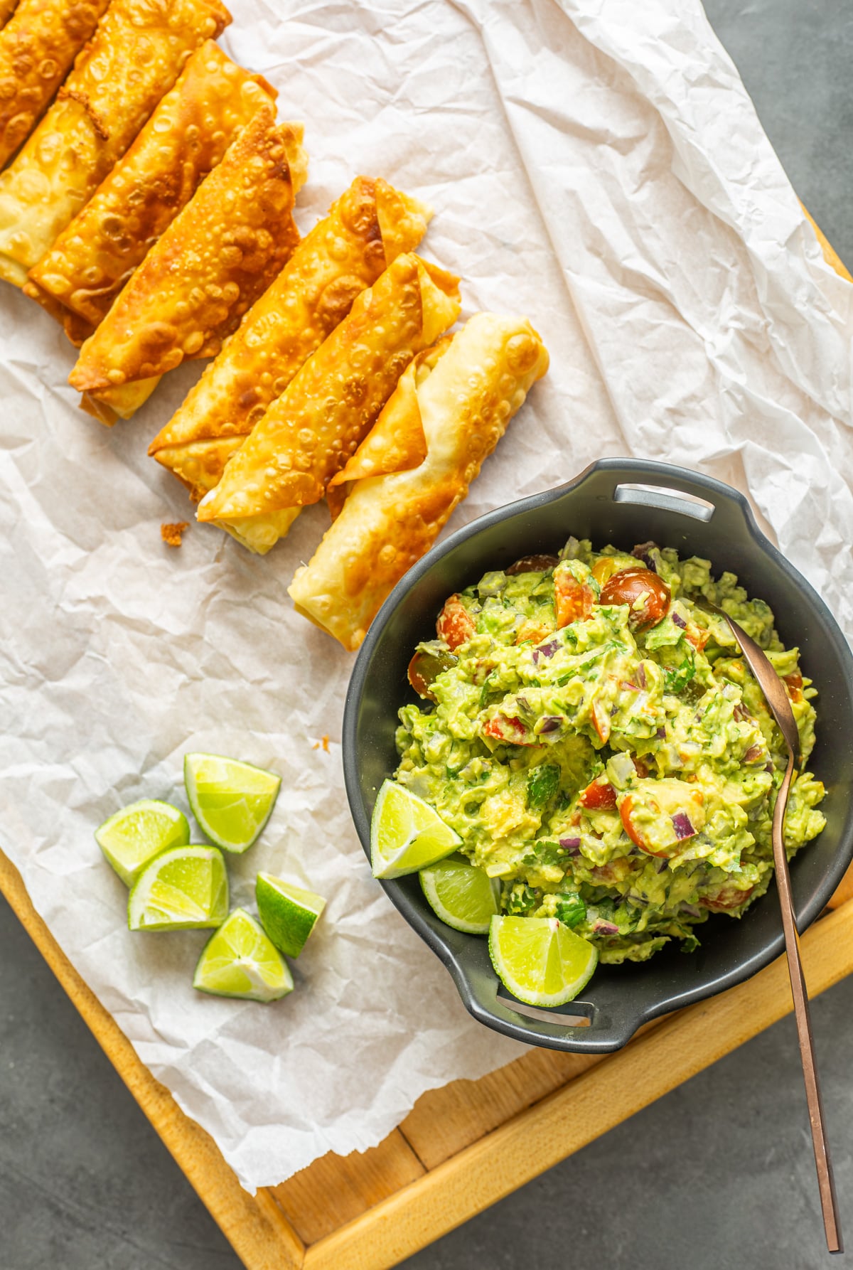 A wood tray with a black ceramic bowl of Peruvian Guacamole | Salsa de Palta along with teque&ntilde;os.