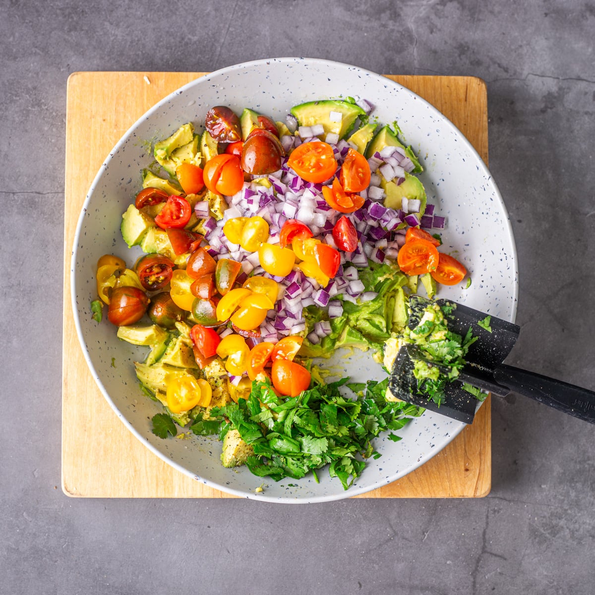 The Peruvian guacamole ingredients in a light grey bowl being mashed.