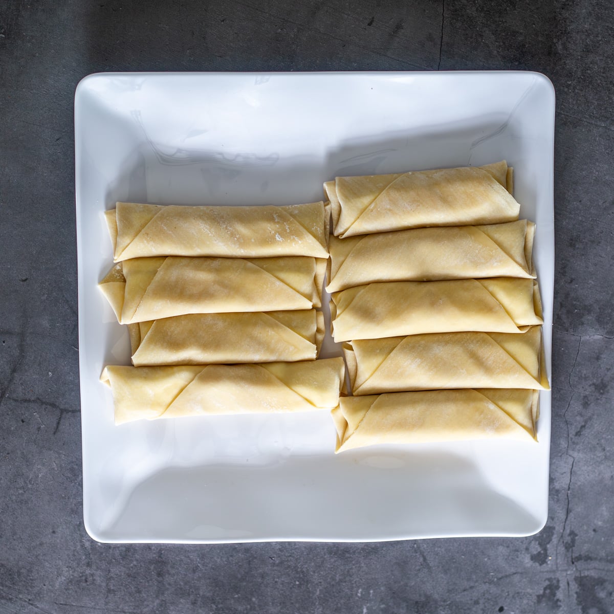 A white plate with 9 cheese teque&ntilde;os.