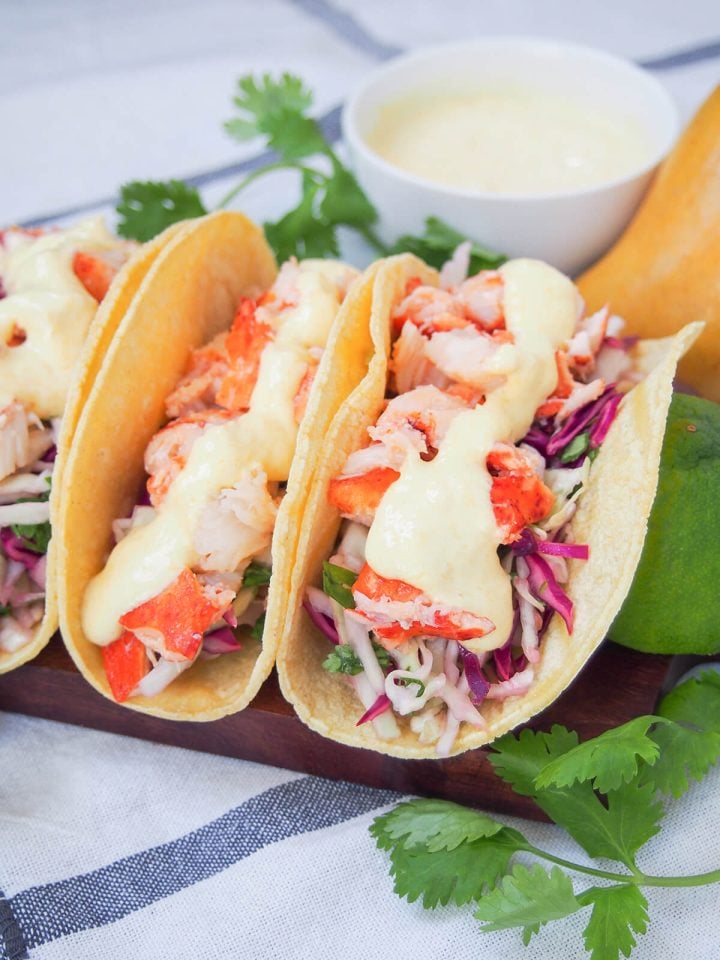 Two lobster tacos in flour tortillas with fresh toppings.
