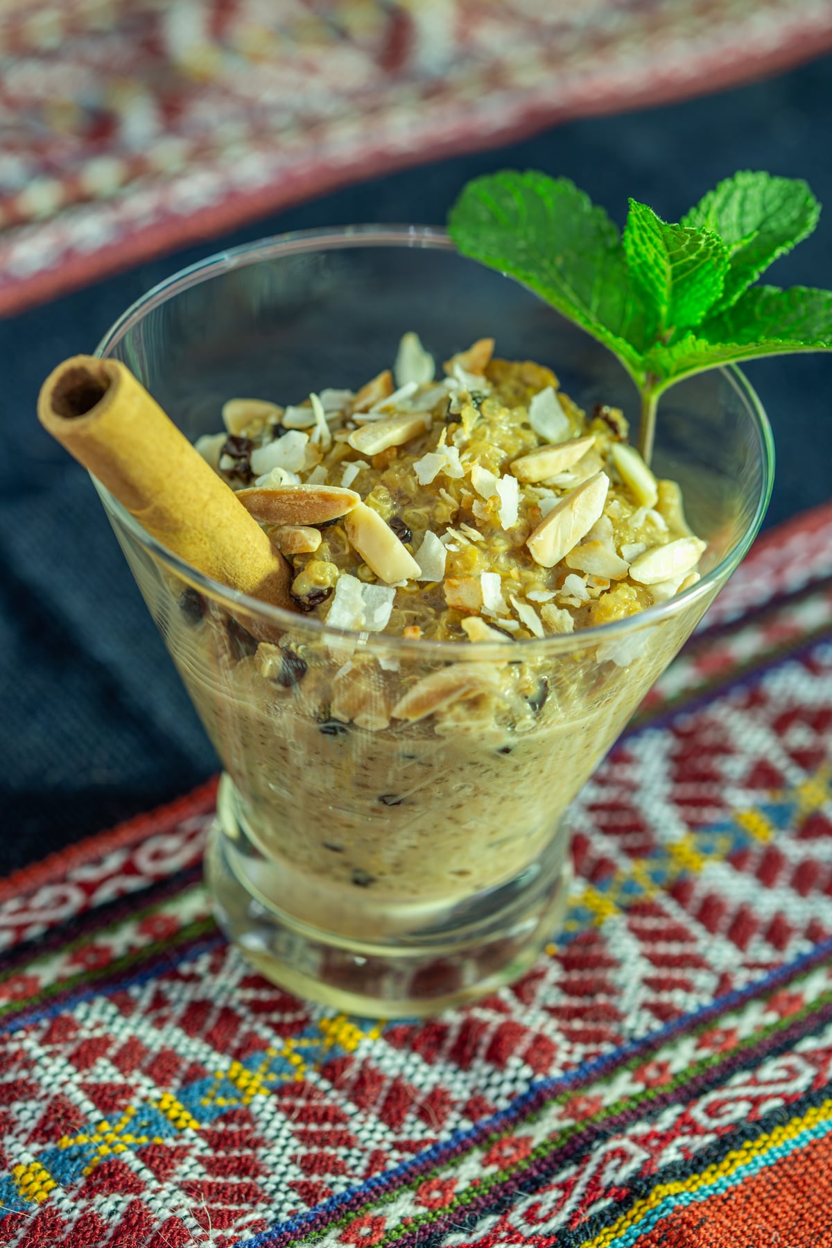 A close up of 1 glass with Peruvian fusion quinoa con leche on a Peruvian textile.