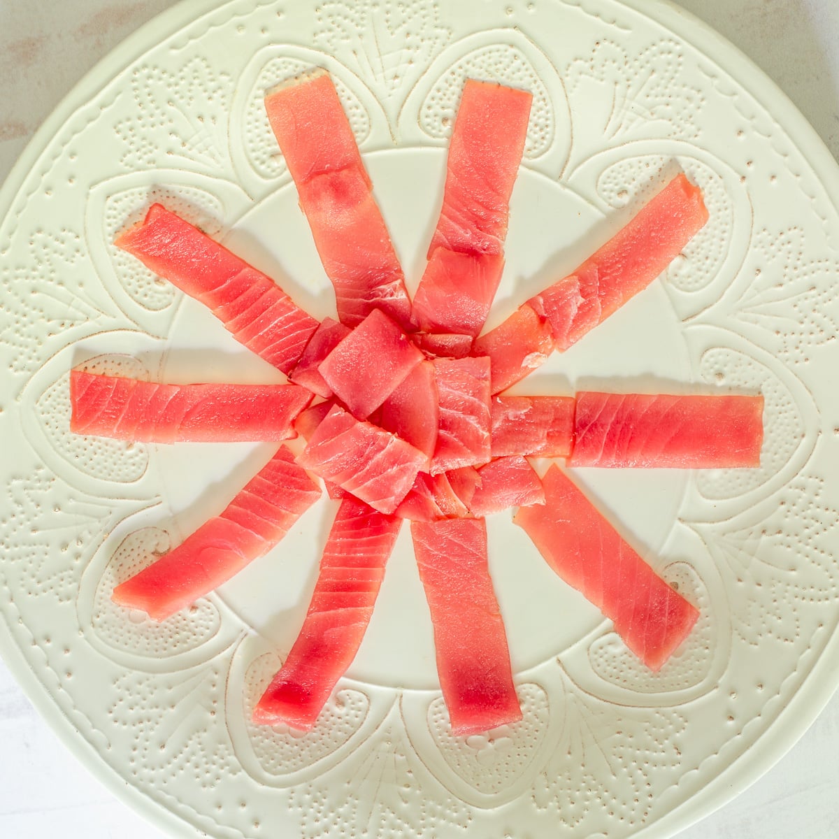A white ceramic plate with very thin-sliced ahi tuna for the tuna tiradito.