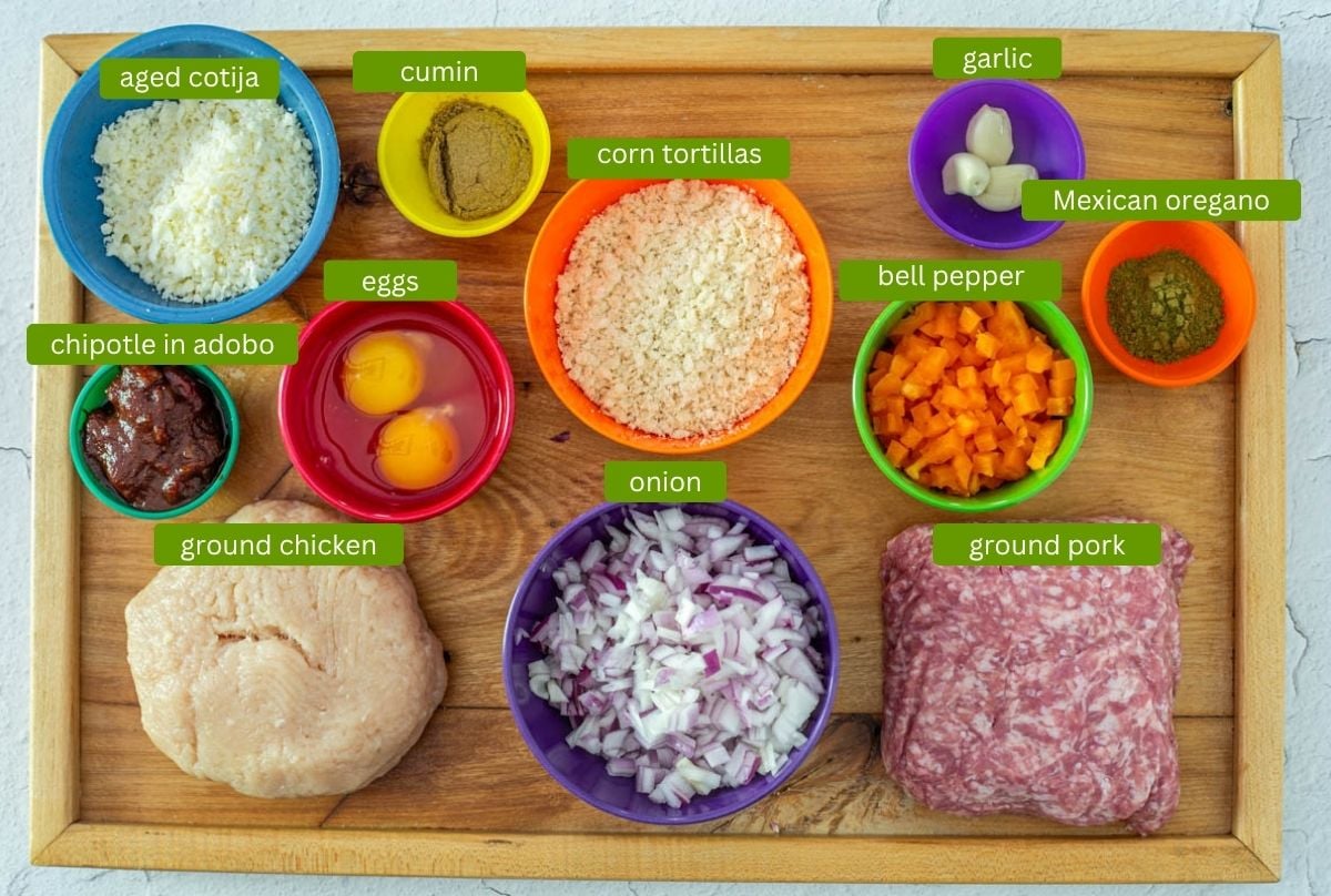 Ingredients for a healthy Mexican meatloaf including ground chicken and ground pork, chipotle peppers, and corn tortillas.