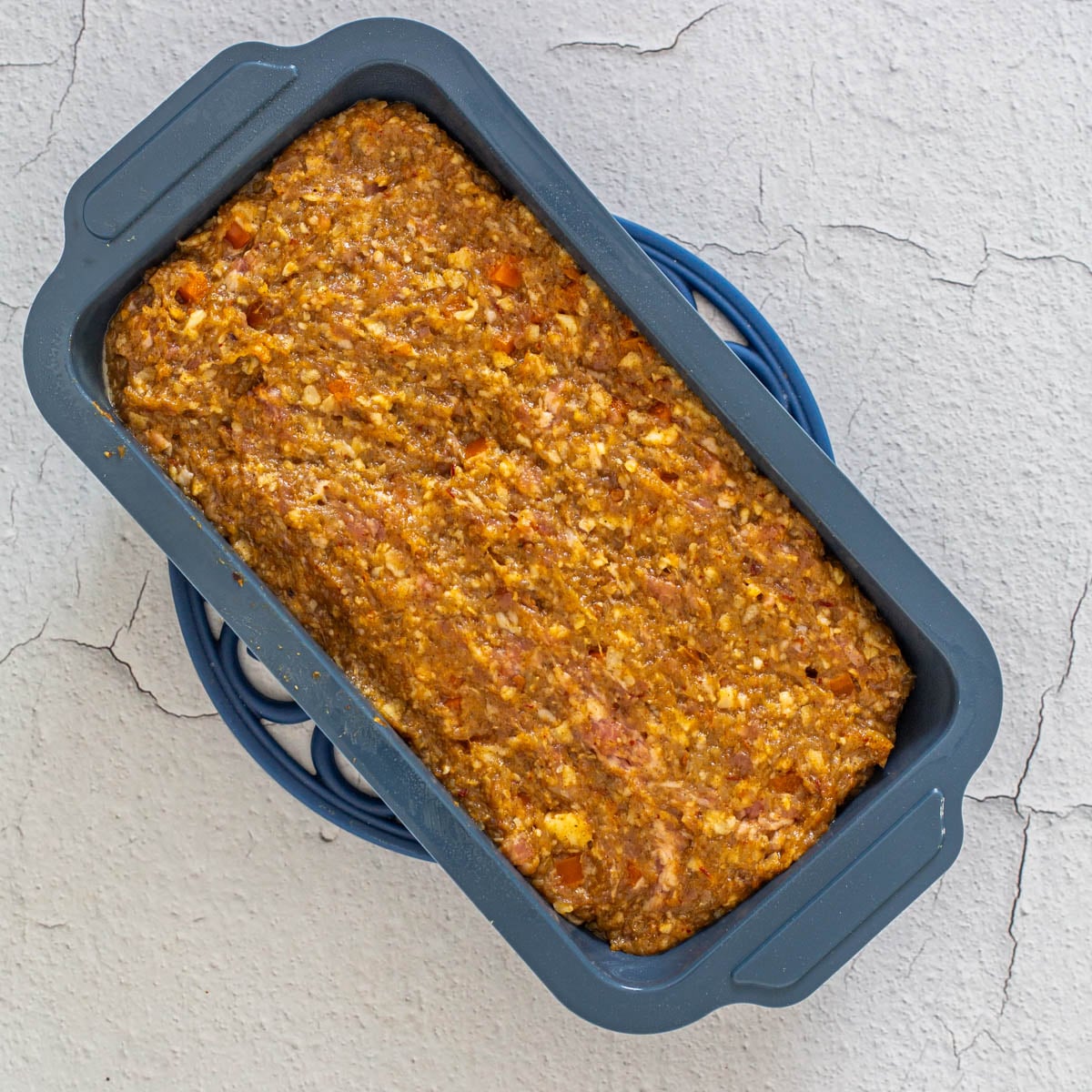 Step 4 - the healthy meatloaf ingredients are placed in a blue-grey silicone loaf pan.