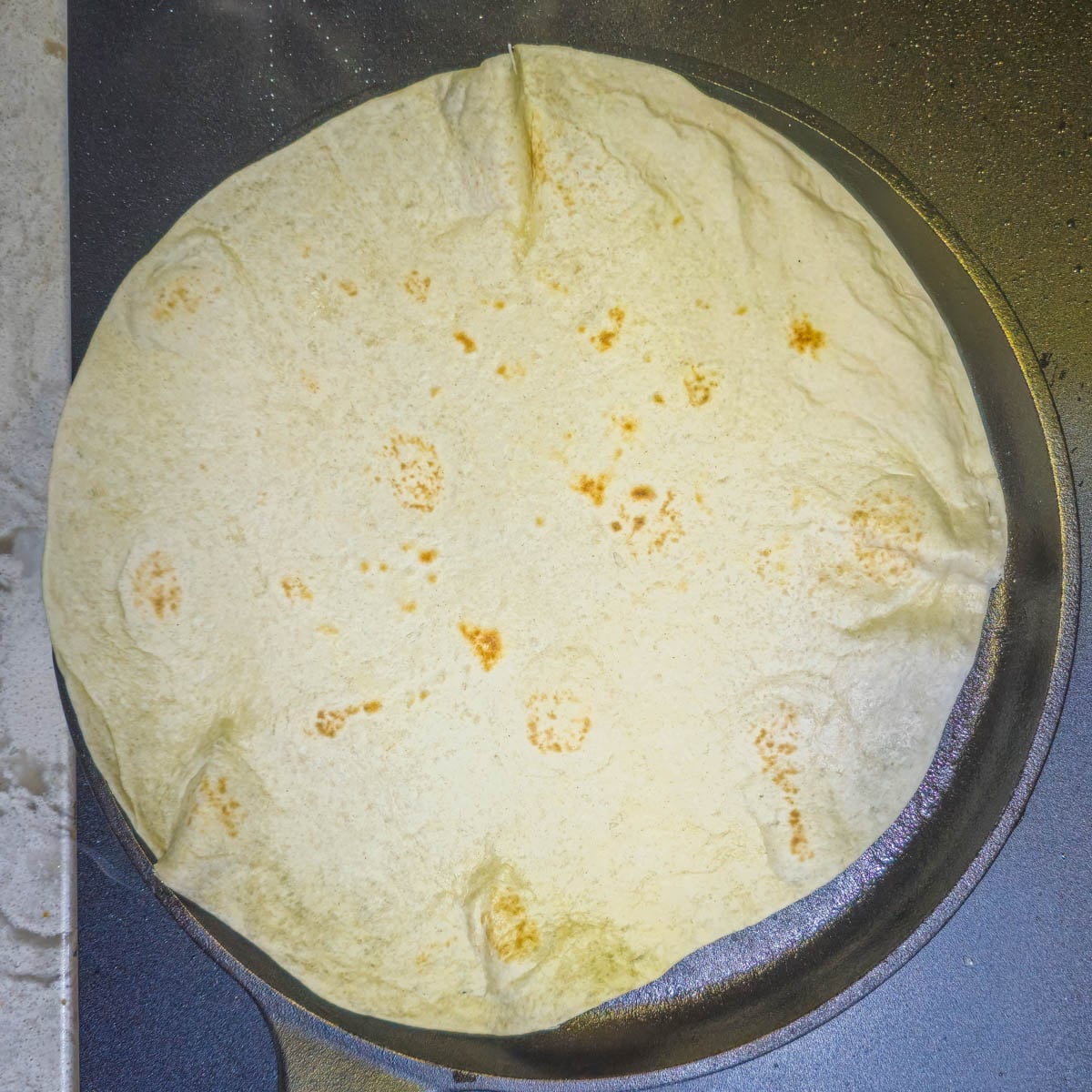 Step 1 - Heat a flour tortilla on a dry cast iron skillet or comal.