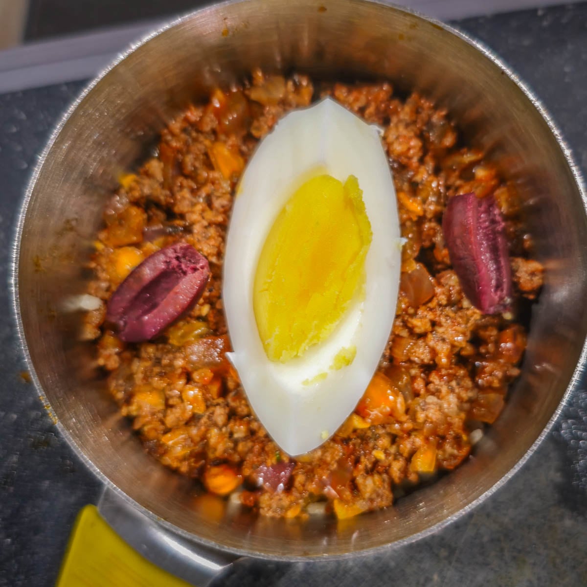 A portion of hard-cooked egg and olives are added on top of the meat mixture.