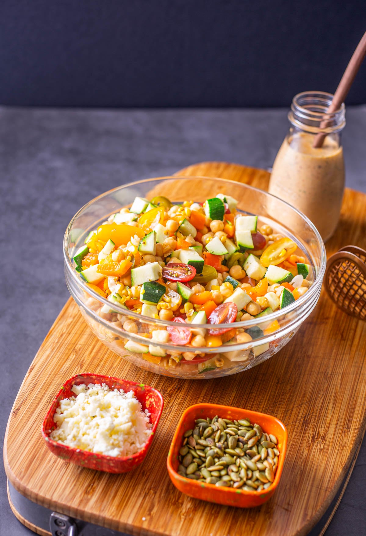 The Mexican chickpea salad with small bowls of pepitas, cotija, and a glass jar of chipotle ranch.
