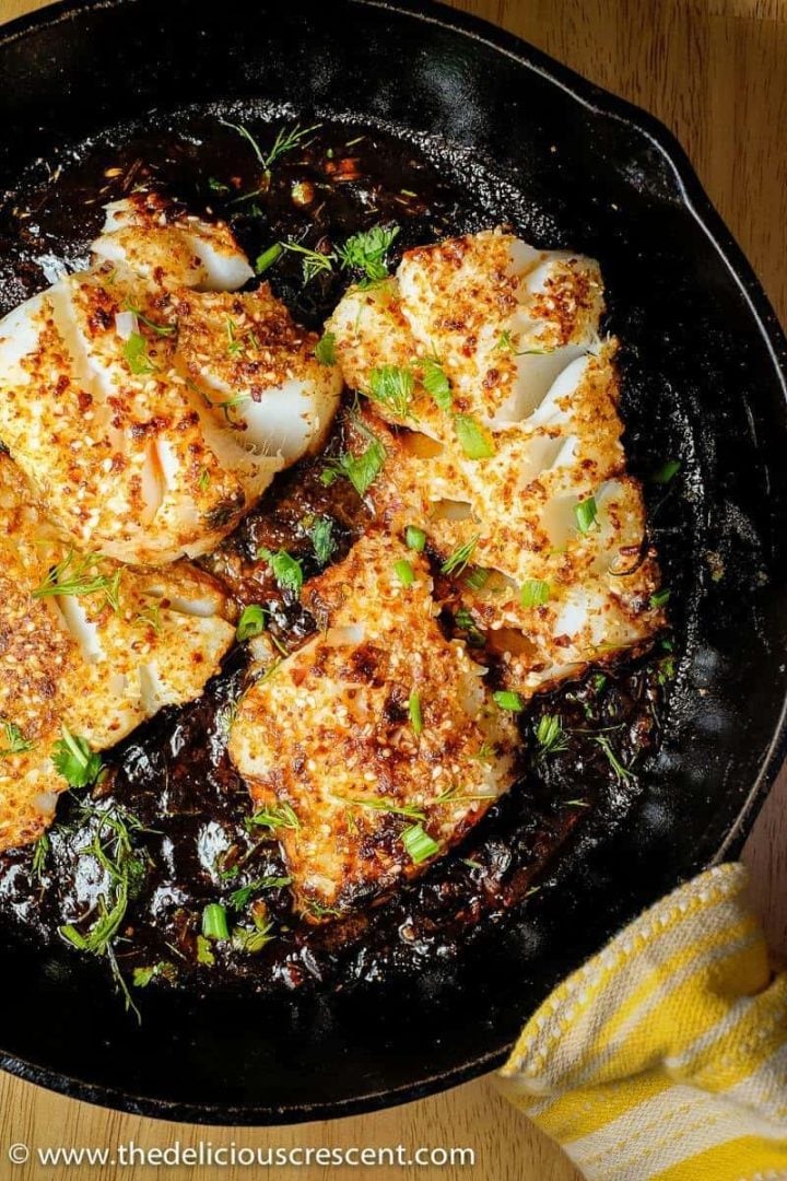 Spicy seared fish with tamarind sauce in a cast iron skillet.