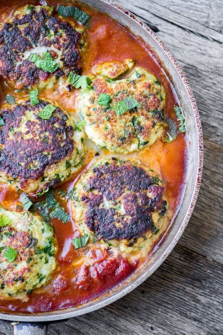 Cod cakes in a rich tomato sauce with a sprinkle of fresh herbs.