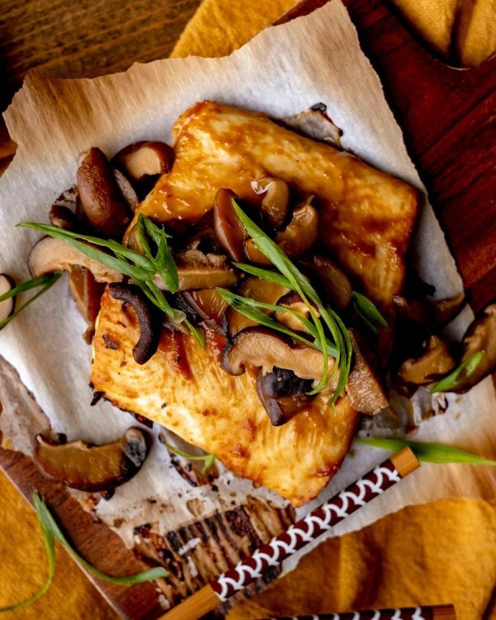 Miso halibut with shiitakes and green onion on parchment with chopsticks.
