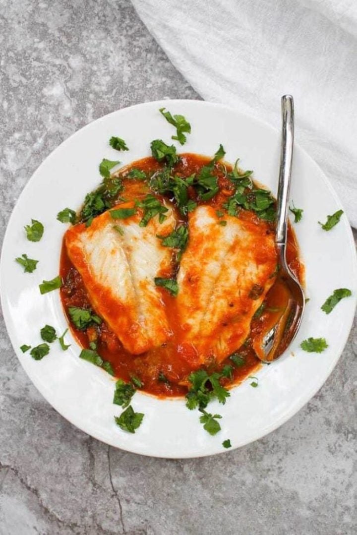 Pumpkin cod curry in a white ceramic bowl with spoon.
