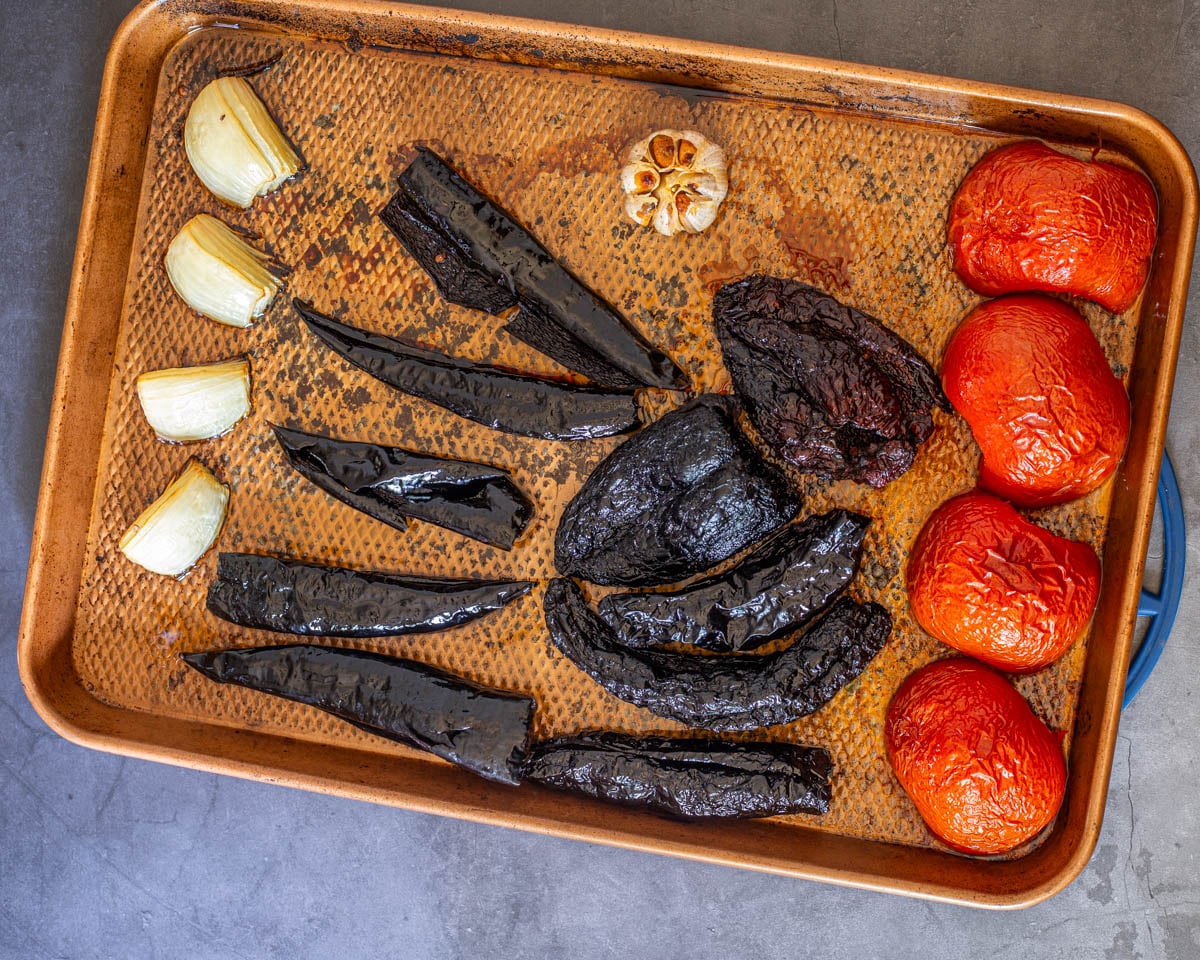 Dried red chiles along with tomatoes, garlic, and onion are roasted on a sheet pan.