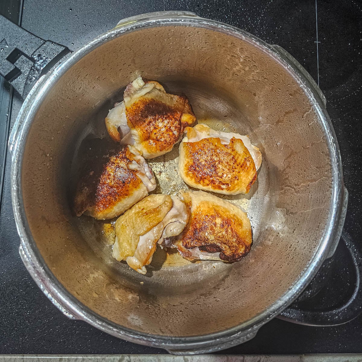 Step 1 - Chicken thighs are browned in a stove top pressure cooker.