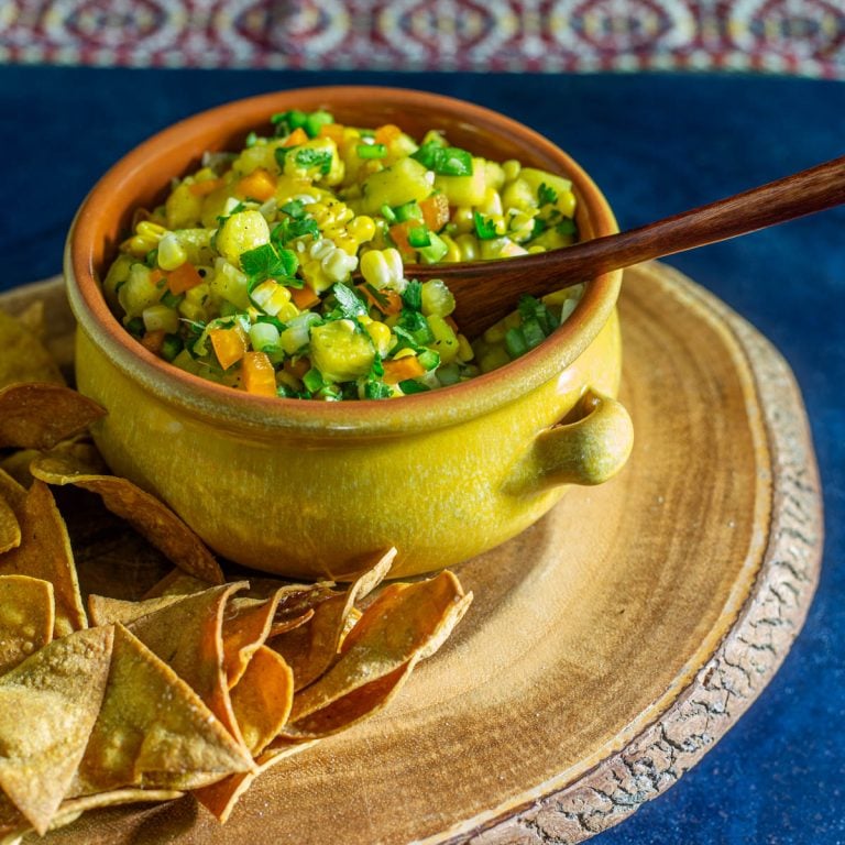 Grilled corn and pineapple salsa in a stoneware bowl with wood spoon.