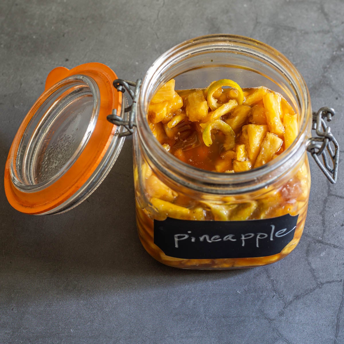 The diced pineapple is mascerated in panela sugar with lime peel in a flip-top jar.